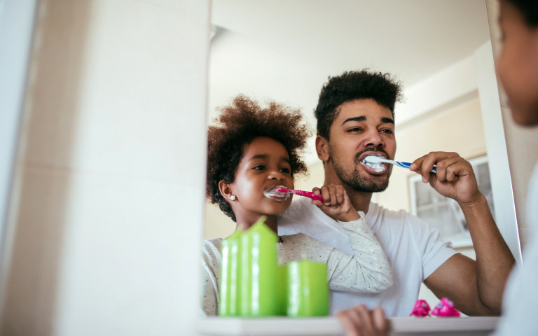 Vader en zoon poetsen tanden voor spiegel