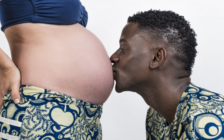 Un homme embrasse le ventre d'une femme enceinte