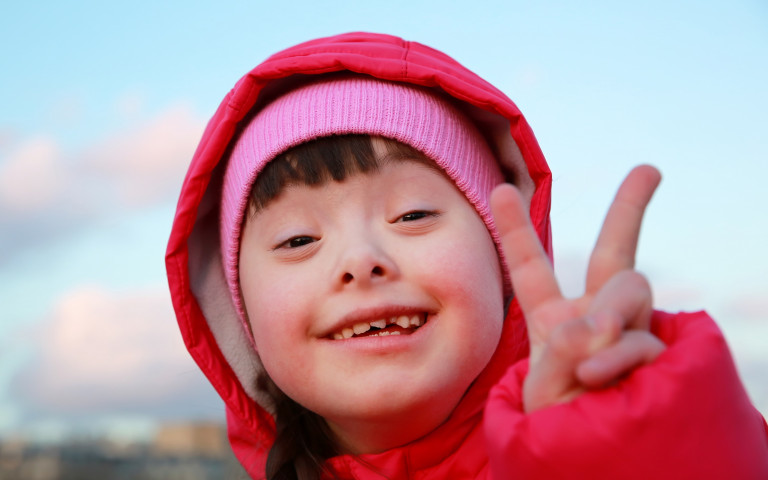 Kind met syndroom van Down maakt V-teken met vingers