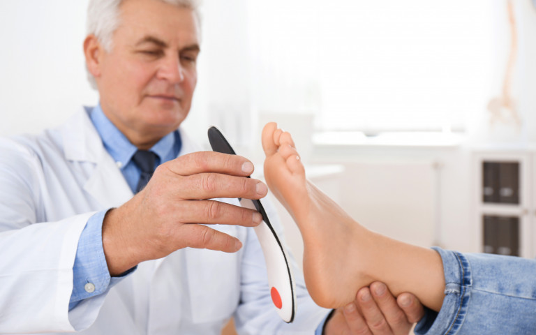 Orthopédiste qui vérifie les semelles de sa patiente