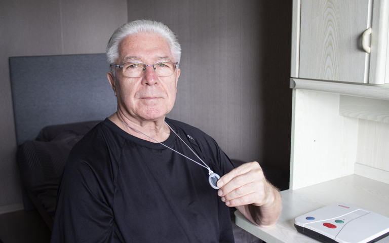 Oudere man met personenalarm halszender en alarmsysteem