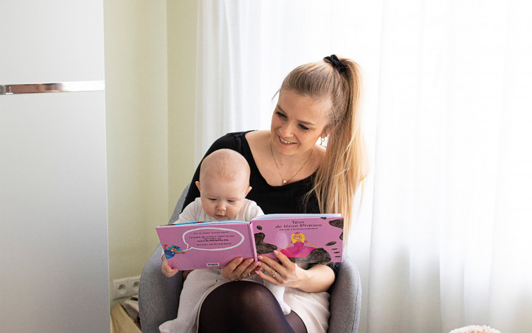 Vrouw en baby op haar schoot kijken samen in een kinderboek