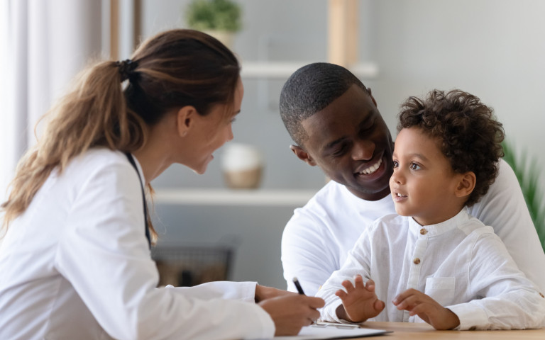 garçon métisse dans les bras de son papa chez le médecin