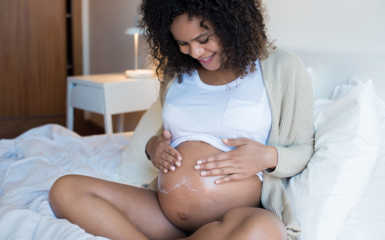 femme enceinte qui met de la crème sur son ventre