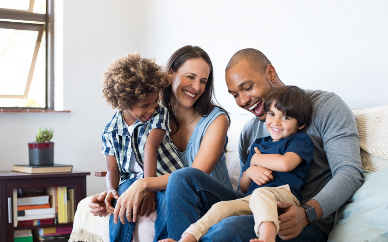 famille souriante assise sur un canapé