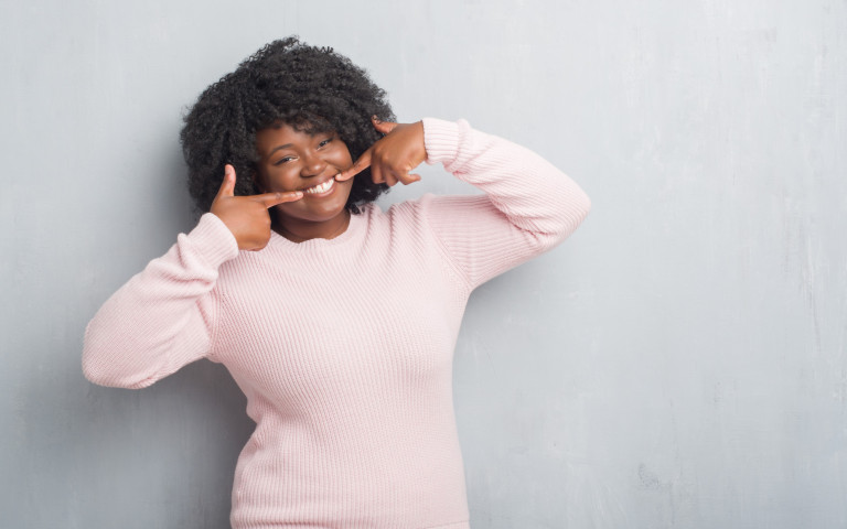 femme en pull rose avec grand sourire