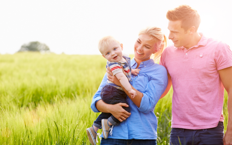 Ouders met kind in de hand op een grasveld.