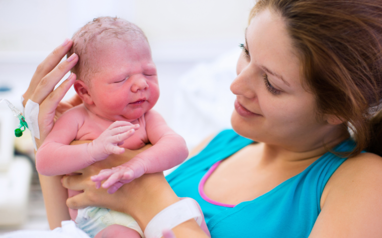 Moeder met pasgeboren baby in de hand in het ziekenhuis.