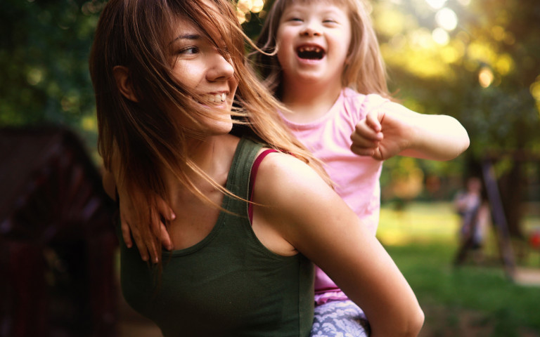 lachend meisje met down met mama in park