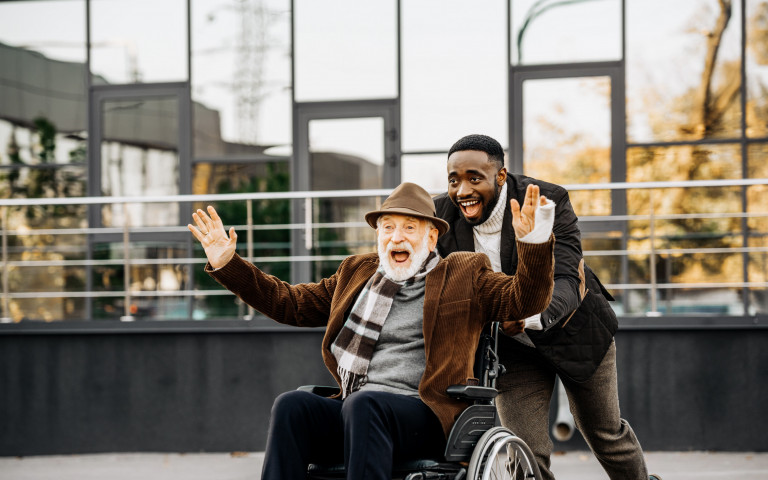 oude man in rolstoel en andere man lachen samen