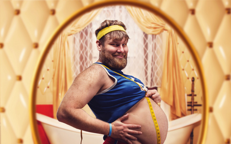 Man met dikke buik voor spiegel