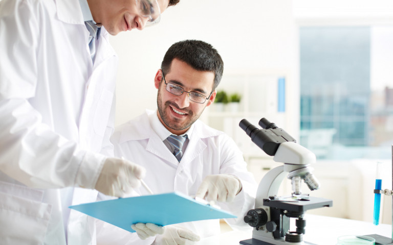 Deux chercheurs discutant avec microscope en avant plan