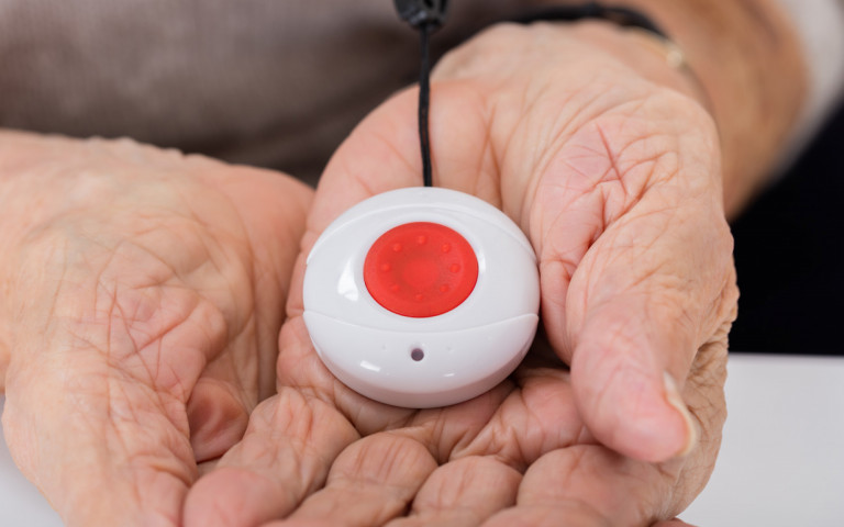 mains ridées tenant un dispositif de télévigilance