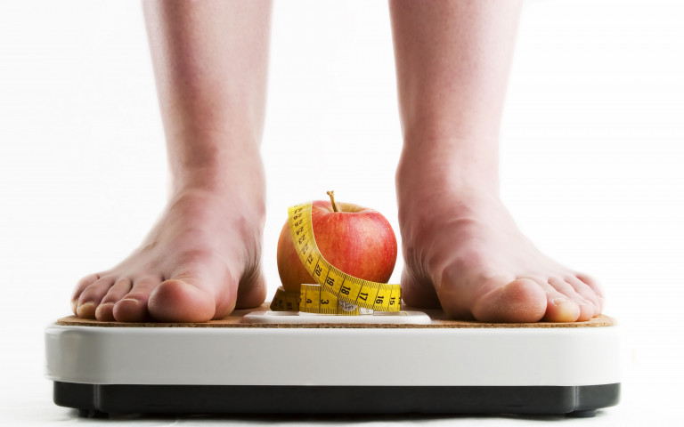 Voeten, appel en lintmeter op een weegschaal
