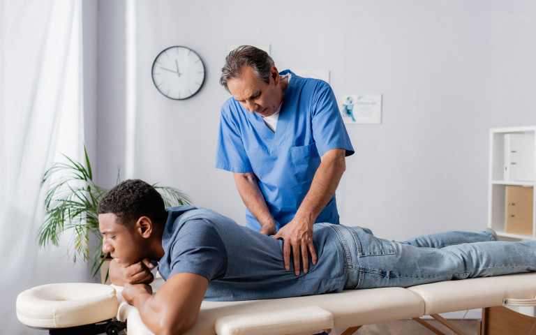 Mannelijke osteopaat behandelt rug van man