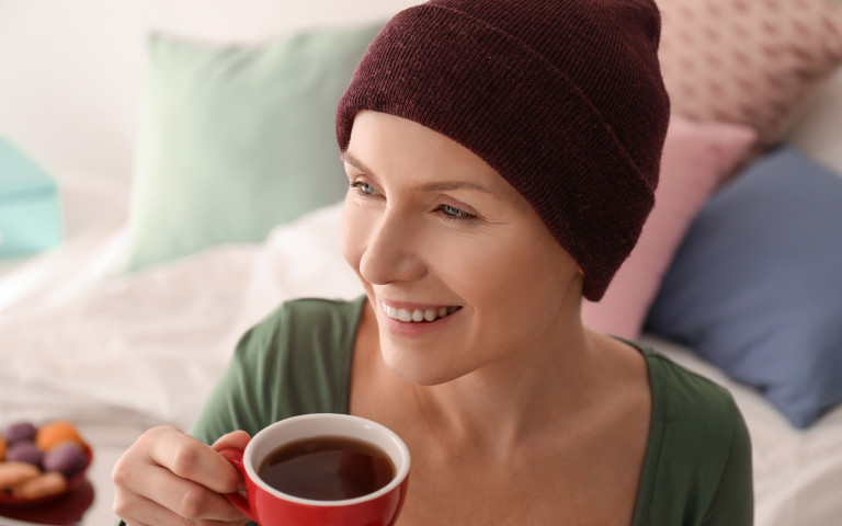 vrouw met muts heeft kanker en drinkt koffie