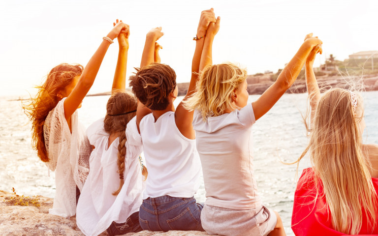 Enfants sur la plage qui lèvent les bras