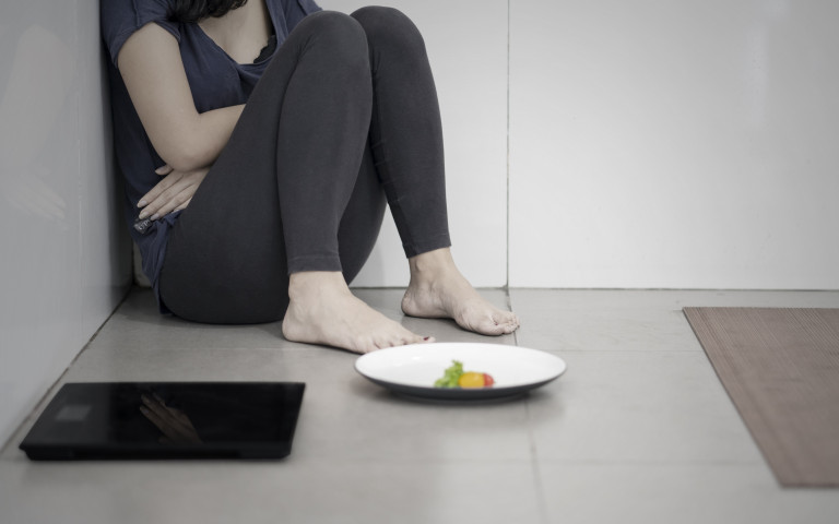 Jeune fille dans un coin avec son assiette et une balance