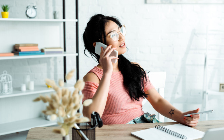femme à son bureau qui téléphone et qui porte des lunettes