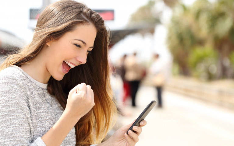 Jonge vrouw happy leest goed nieuws op smartphone