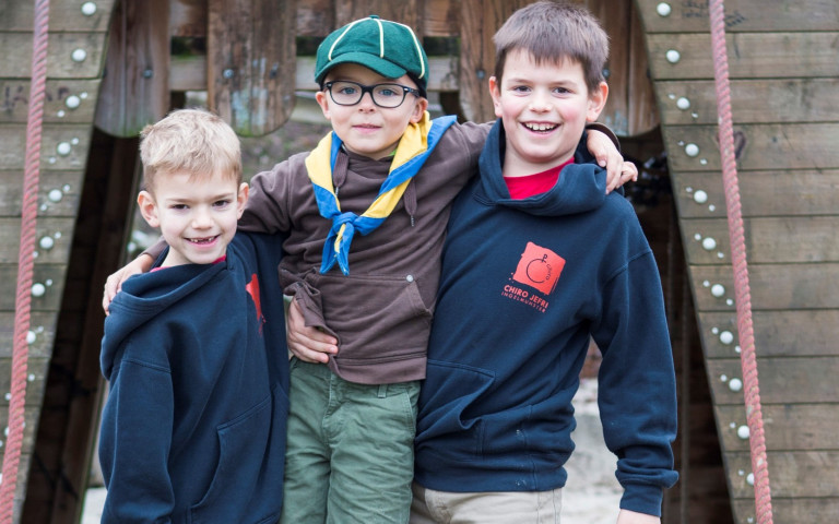 Jongens in chiro uniform houden scouts jongen vast