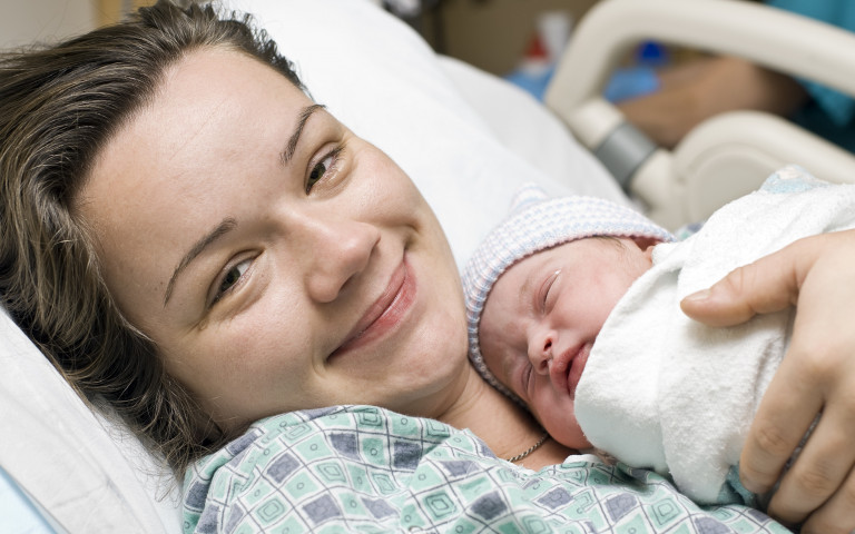 Une maman qui vient d'accoucher dans son lit d'hôpital