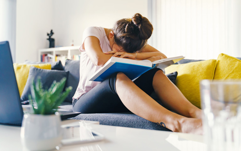 Studente met hoofd in boeken