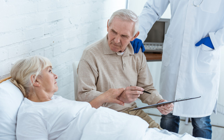 Vrouw in bed met man en dokter