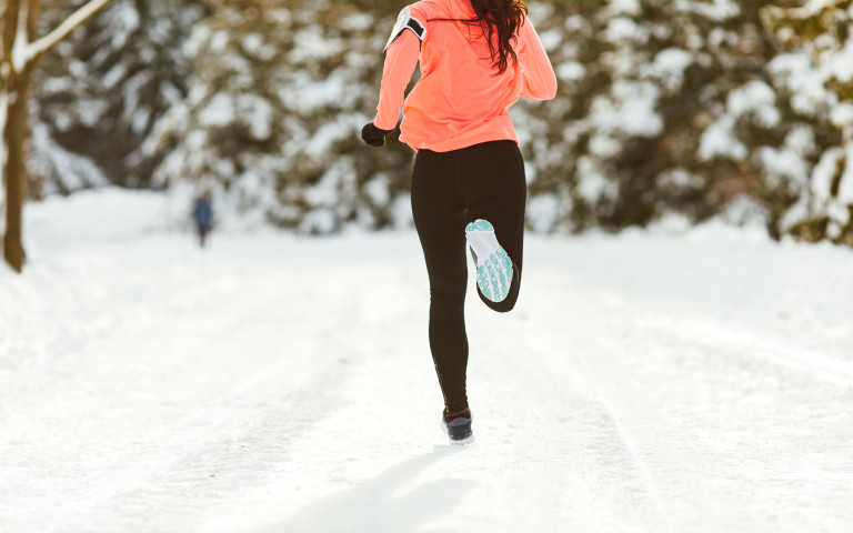 Joggeuse avec pull orange et pantalon noir dans un décor hivernal