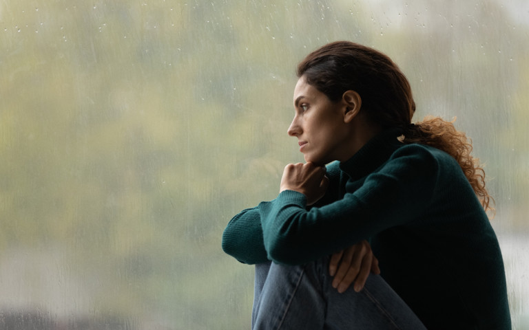 Femme pensive qui regarde par la fenêtre