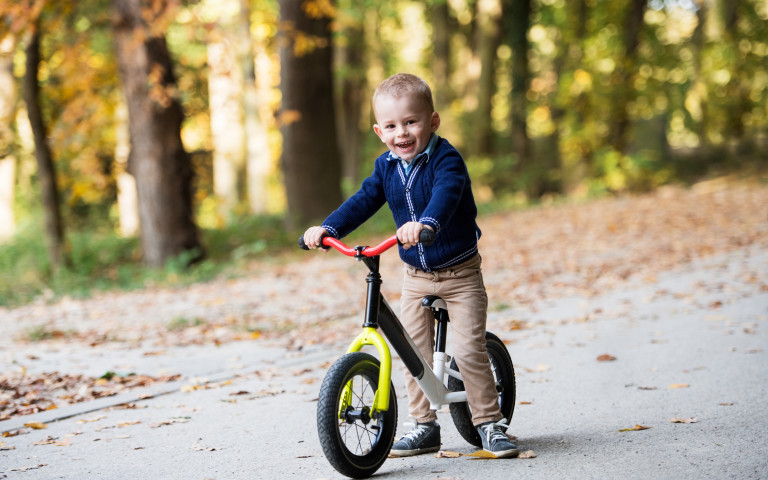 Enfant sur une draisienne dans les bois
