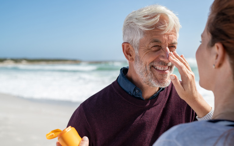 vrouw smeert man in met zonnebrand op het strand