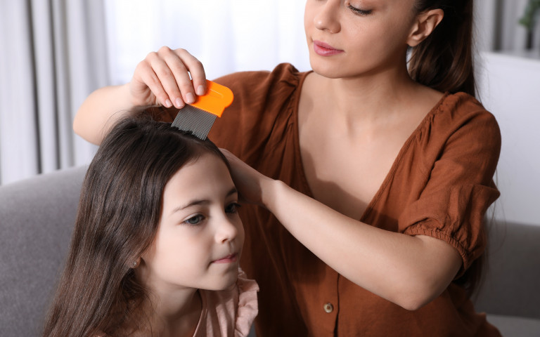 vrouw onderzoekt hoofd kind op luizen 