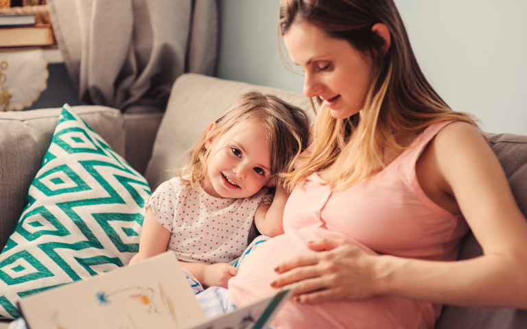 Femme enceinte avec enfant en bas âge assises dans un canapé