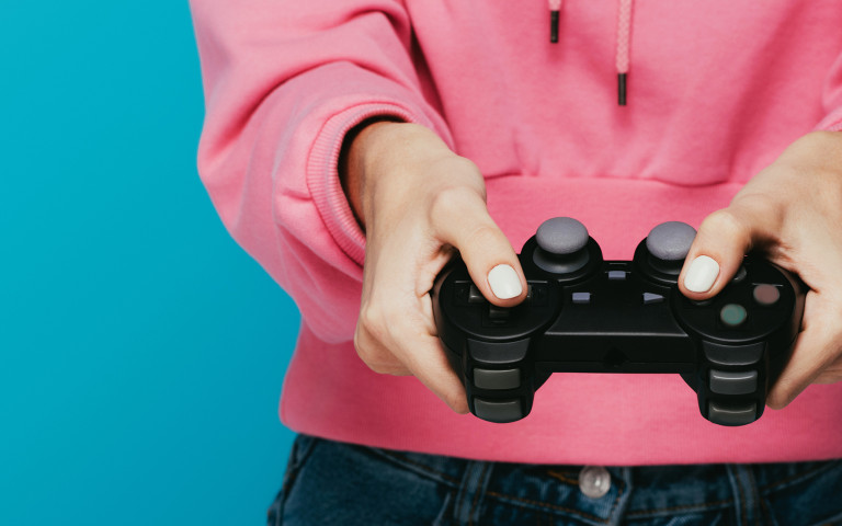 Meisje met roze trui houdt gameconsole vast