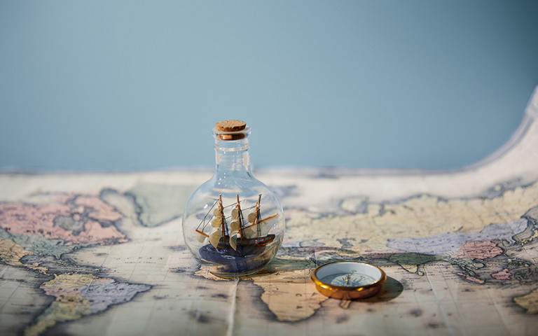 Landkaart met zeeschip in fles en kompas