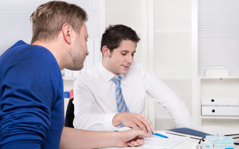 Man aan bureau helpt andere man in terug-naar-werk-traject