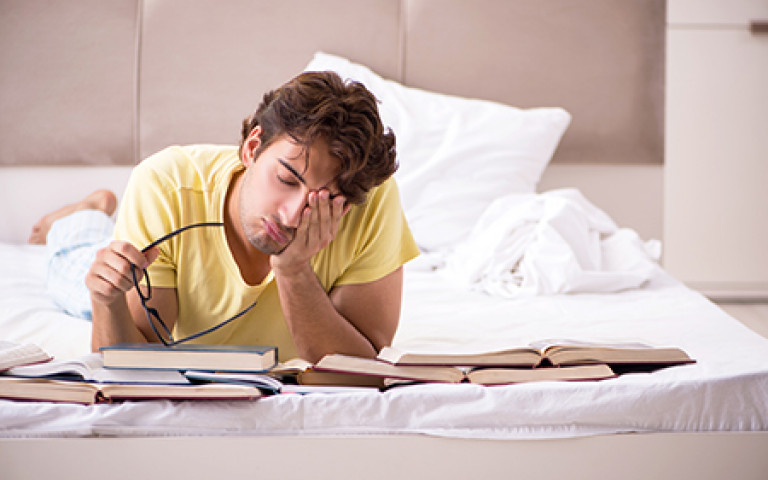 Jeune étudiant qui étudie sur son lit