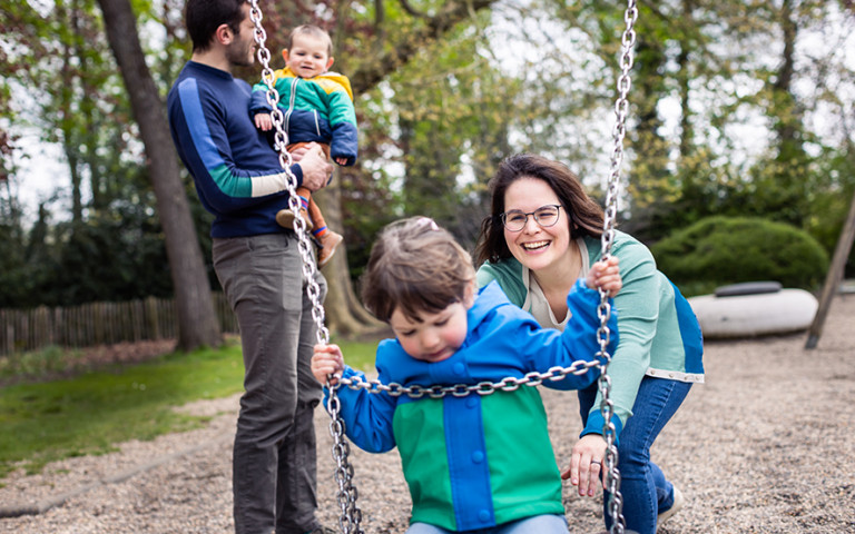 Gezin van vier in de speeltuin op de schommel