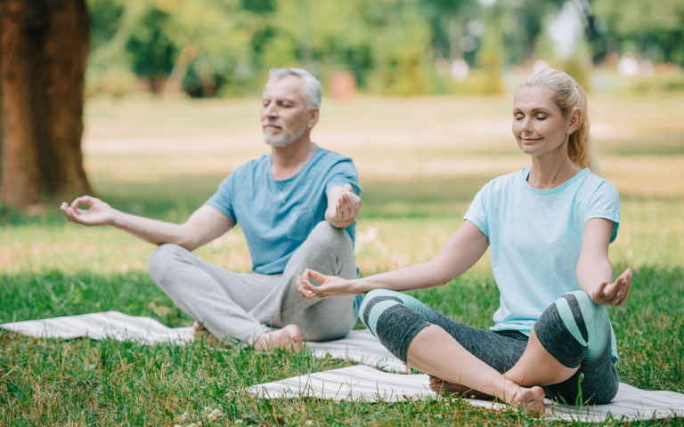 Man en vrouw die yoga buiten doen