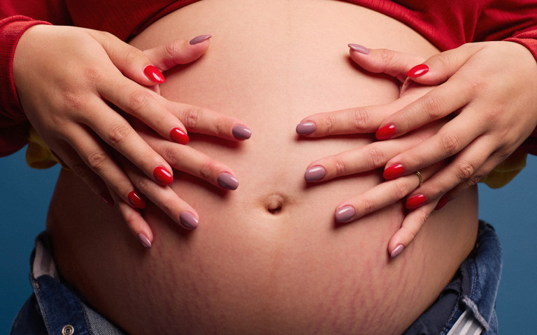 twee mama's leggen handen op zwangere buik