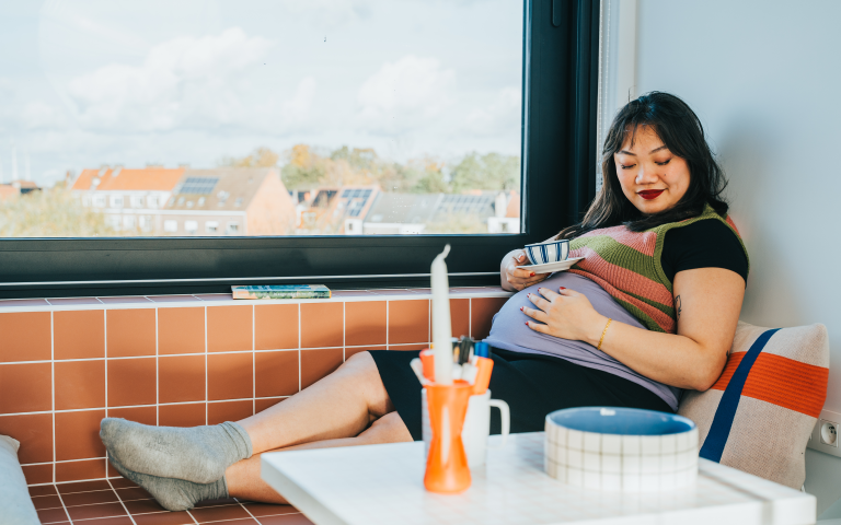 Zwangere vrouw drinkt een theetje op de bank
