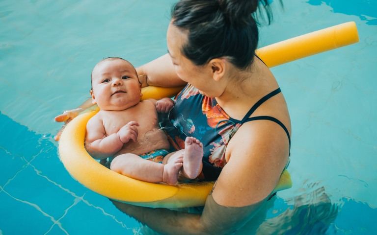Mama gaat met haar baby babyzwemmen in zwembad