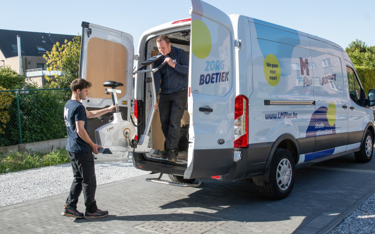 Medewerkers uitleendienst halen hometrainer uit bestelwagen