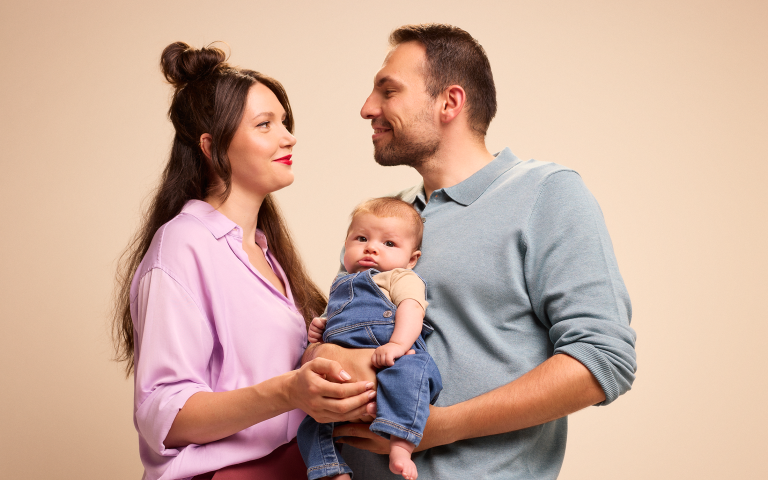 Koppel kijkt lievend naar elkaar met baby in de arm