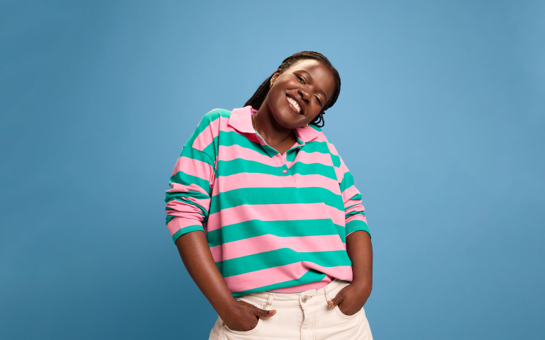 Jonge vrouw van poseert en lacht naar de camera