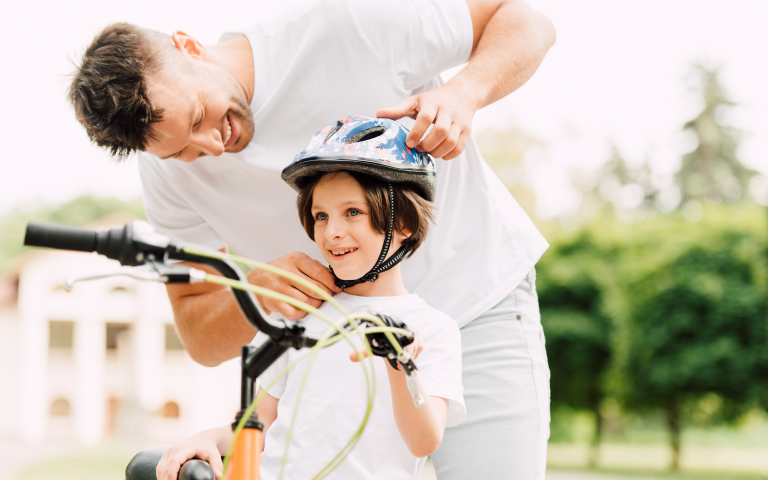 Papa zet fietshelm goed vast op het hoofd van zijn zoon