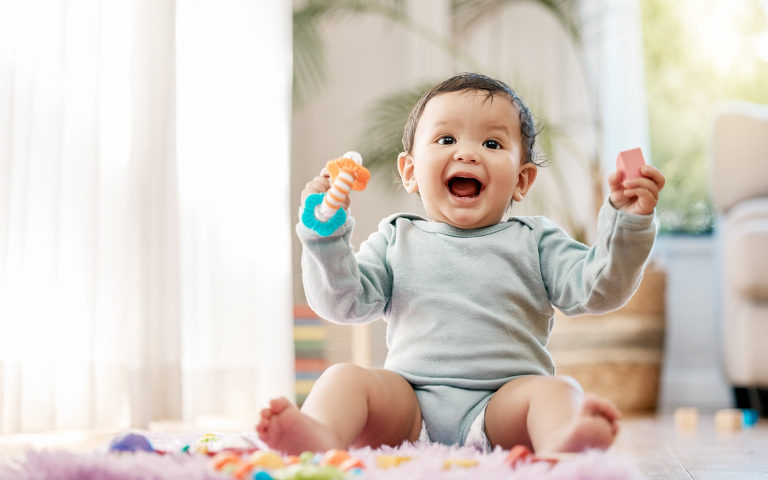  Lachende baby zittend op een speelmat met speelgoedje vast