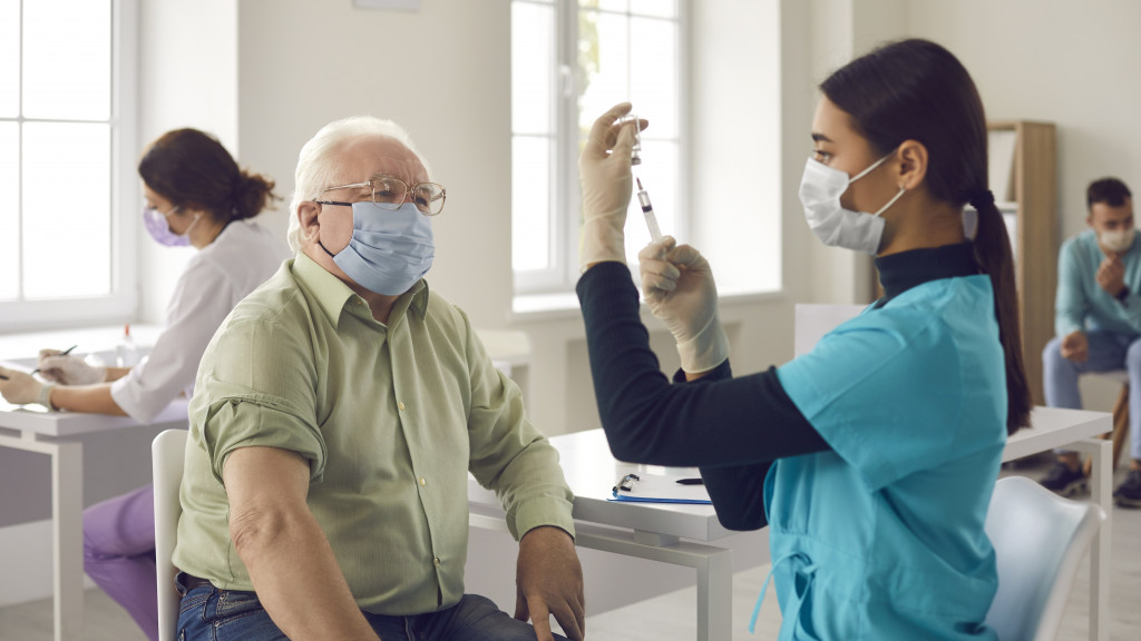 Oudere man krijgt vaccin van verpleegkundige