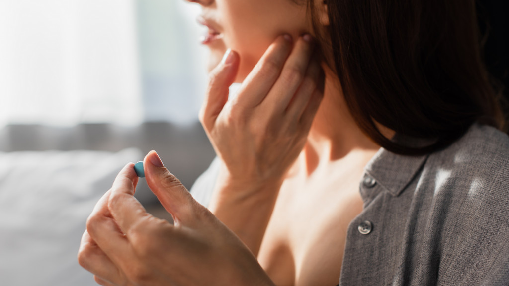 Femme avec douleur à la mâchoire prend la pilule